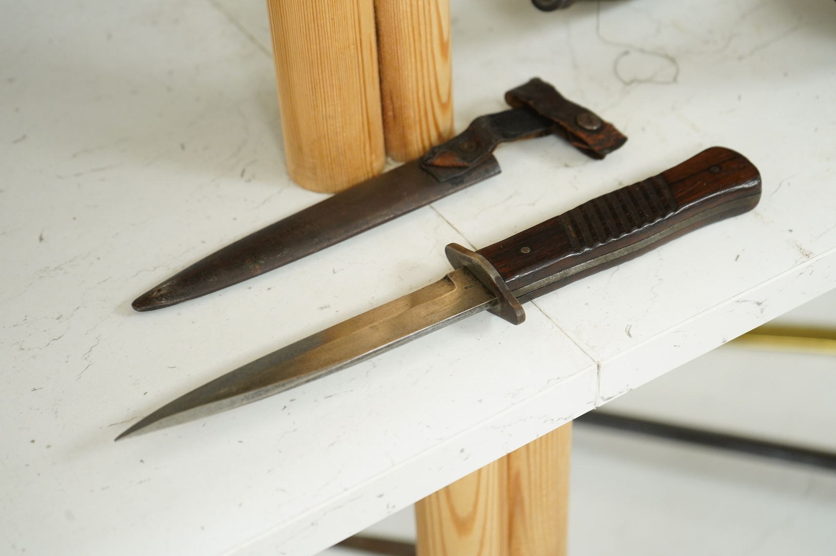 A First World War German Fighting Knife, with two piece wooden grip and steel cross guard, in original steel scabbard with leather belt loop mount, single edged blade with makers mark to one side; Gottlieb Hammesfahr, So